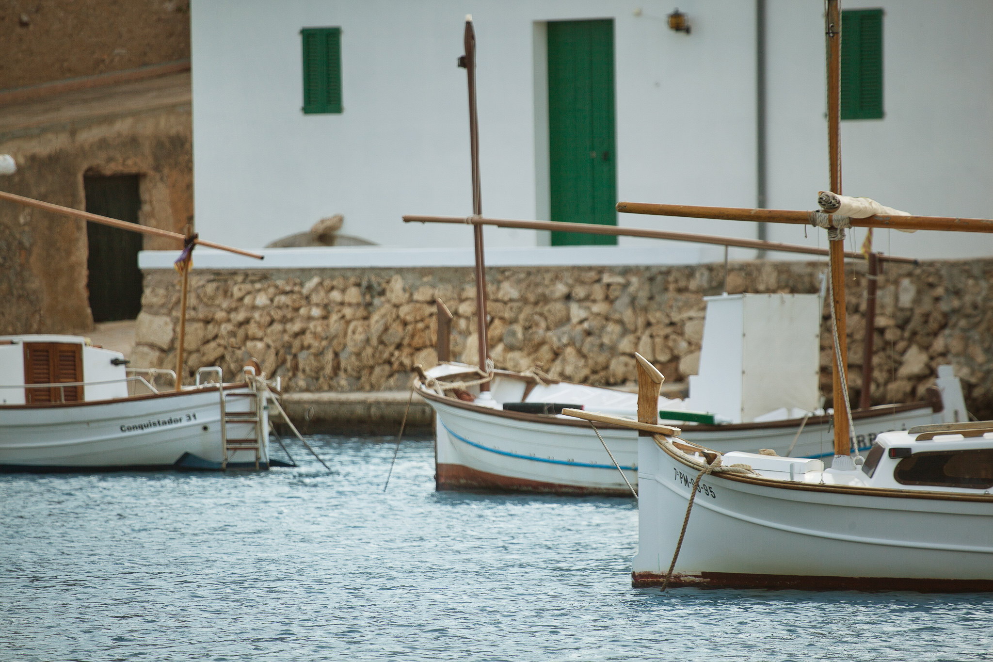 Puerto de cala dor con barcos típicos y casas blancas